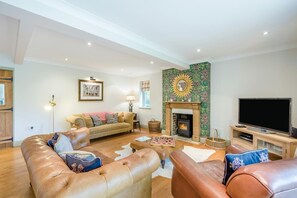 A living room with a fireplace, leather sofas, a television, and a chessboard. - 3 Bed in Ufford (oc-sfmea) (Ufford)