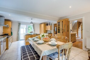 Une cuisine spacieuse avec un coin repas, des meubles de cuisine en bois et un escalier menant à l’étage supérieur.