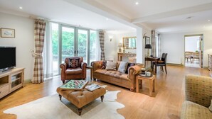 A spacious living room with a leather sofa, a coffee table, and a television. - 3 Bed in Ufford (oc-sfmea) (Ufford)