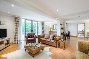A spacious living room with a leather sofa, a coffee table, and a television. - 3 Bed in Ufford (oc-sfmea) (Ufford)