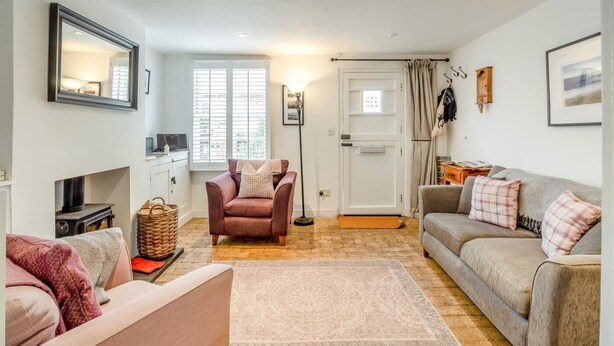 Un salon chaleureux avec une cheminée, un canapé, un fauteuil et une grande fenêtre.