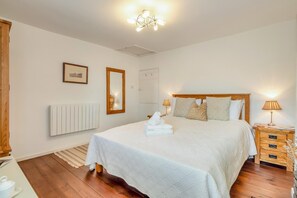 A bedroom with a large bed, bedside lamps, a mirror, and a radiator. - 2 Bed in Orford (oc-sfcto) (Orford)