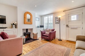 Ein Wohnzimmer mit Kamin, Fernseher, einer Couch und einer Stehlampe.