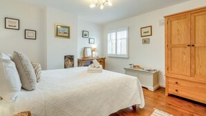 Une chambre à coucher avec un grand lit, une armoire en bois, un bureau avec une lampe et des tableaux encadrés accrochés aux murs.