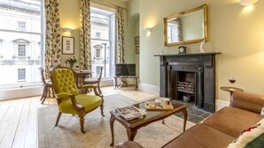 A living room with a fireplace, a green armchair, a sofa, and a television. - 1 Bed in Bath (oc-bhr5) (Bath)
