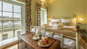 A hotel room with a bed, bedside table with tea set, breakfast tray, and a view of the city through large windows. - 1 Bed in Bath (oc-bhr5) (Bath)