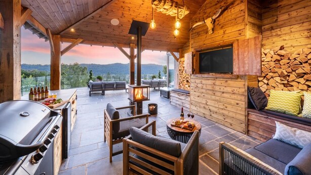 Une terrasse en bois avec un barbecue, des sièges et une cheminée.
