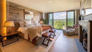 Une chambre à coucher avec un grand lit, un canapé, un fauteuil et une cheminée.