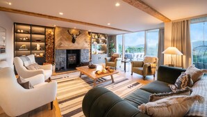 Un salon spacieux doté d’une cheminée, de sièges confortables et d’une grande fenêtre offrant une vue sur l’extérieur.