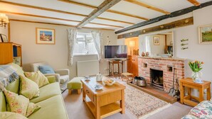 A cozy living room with a sofa, a wooden coffee table, a fireplace, and a television. - 3 Bed in Frostenden (oc-sfhms) (Frostenden)