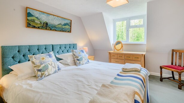 A bedroom with a large bed, a wooden dresser, a chair, and a window with a view of greenery. - 3 Bed in Frostenden (oc-sfhms) (Frostenden)