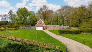 A house with a red brick exterior, a white garage, and a gravel driveway leading to a wooden fence. - 3 Bed in Frostenden (oc-sfhms) (Frostenden)