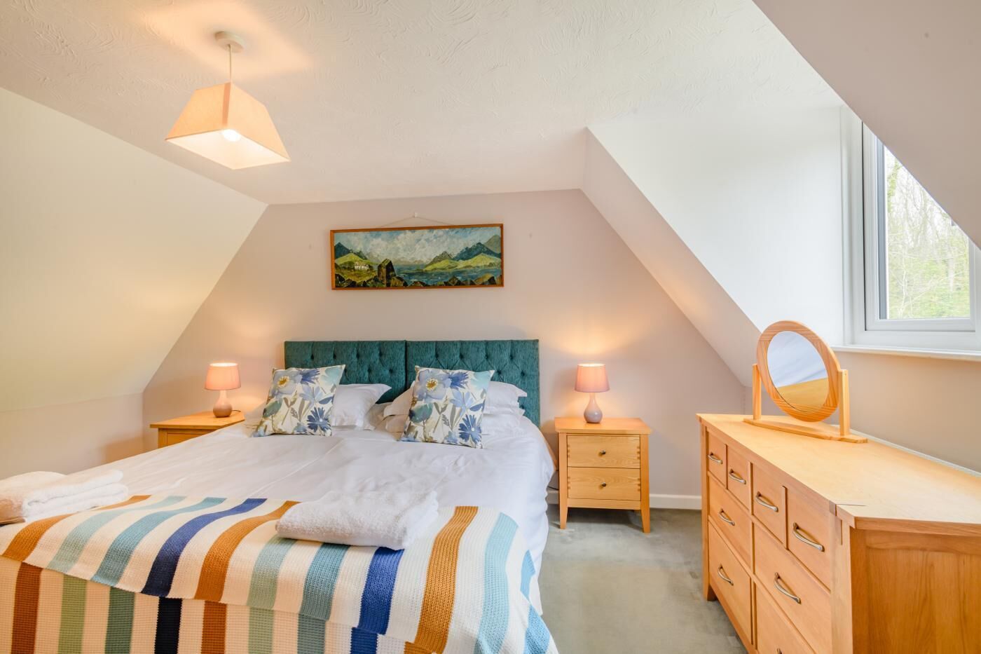 A bedroom with a bed, two bedside tables, a dresser, a mirror, and a painting on the wall.