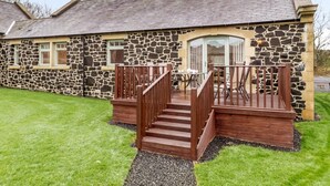 A stone building with a wooden deck and steps leading to a door. - 3 Bed in Alnwick (oc-80479) (Newton-by-the-Sea)
