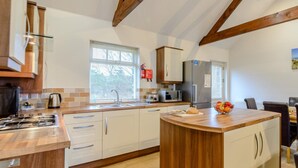 A modern kitchen with white cabinets, a wooden island, and a built-in microwave. - 3 Bed in Alnwick (oc-80479) (Newton-by-the-Sea)