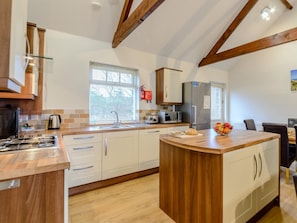 A modern kitchen with white cabinets, a wooden island, and a built-in microwave. - 3 Bed in Alnwick (oc-80479) (Newton-by-the-Sea)