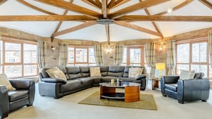 A spacious living room with a large L-shaped sectional sofa, a wooden coffee table, and a stone fireplace. - 4 Bed in Alnwick (oc-80484) (Newton-by-the-Sea)
