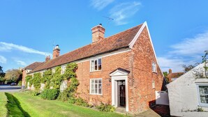 A two-story brick house with a sloped roof, a front door, and a small garden area. - 2 Bed in Orford (oc-sflis) (Orford)