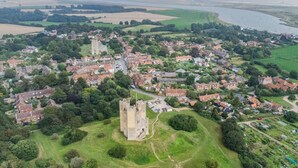 An aerial view of a historic town with a prominent castle, narrow streets, and a river. - 2 Bed in Orford (oc-sflis) (Orford)