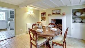 A dining room with a round wooden table, four chairs, and a fireplace. - 2 Bed in Iken (oc-sfboo) (Iken)