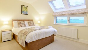 A bedroom with a bed, two bedside tables, a radiator, and a window with a view. - 2 Bed in Alnwick (oc-80494) (Newton-by-the-Sea)