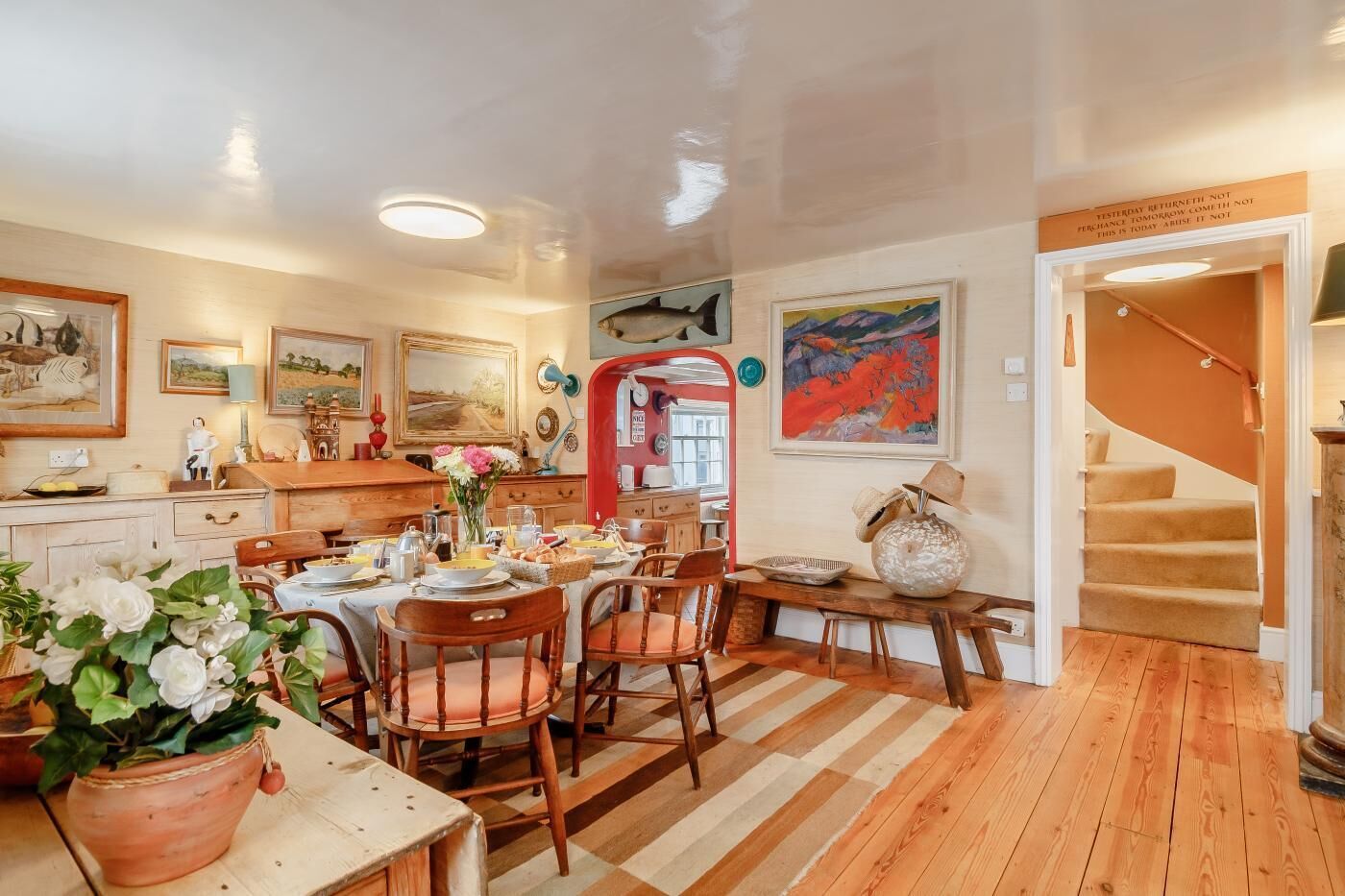 Un comedor acogedor con muebles de madera, una puerta roja y una escalera que sube.