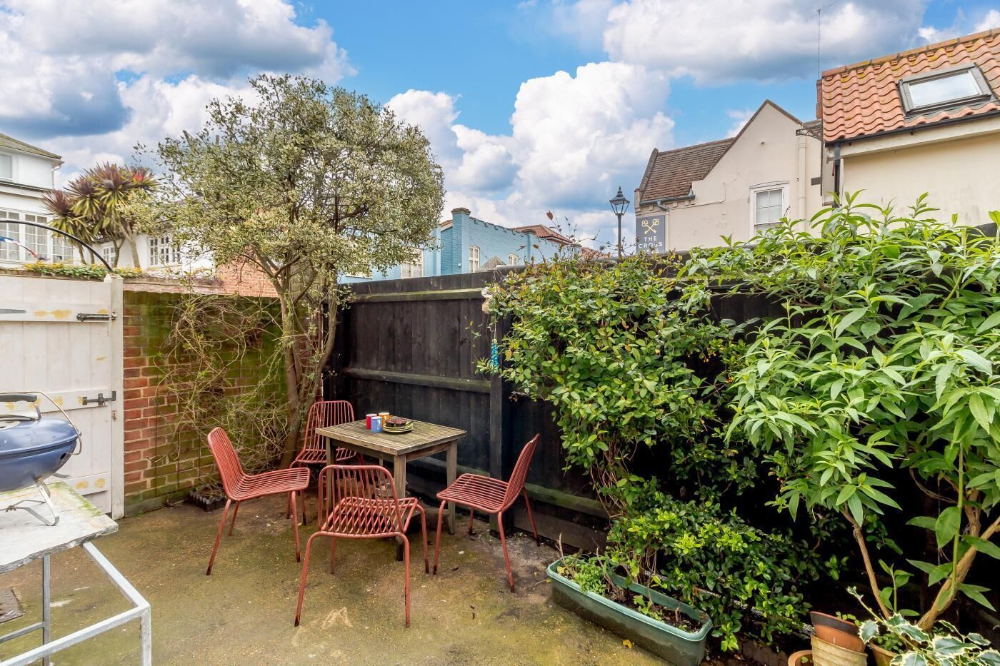 A patio with a table and chairs, surrounded by a wooden fence and greenery.