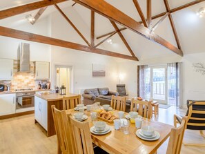 A spacious kitchen with wooden beams, a dining area with a breakfast setting, and a living area with a sofa and a chair. - 3 Bed in Alnwick (oc-80490) (Newton-by-the-Sea)