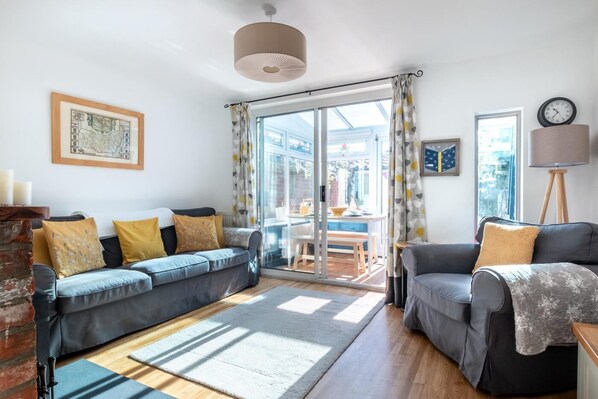 Ein modernes Wohnzimmer mit einer Couch, Sesseln, einem Kamin und Blick ins Freie.