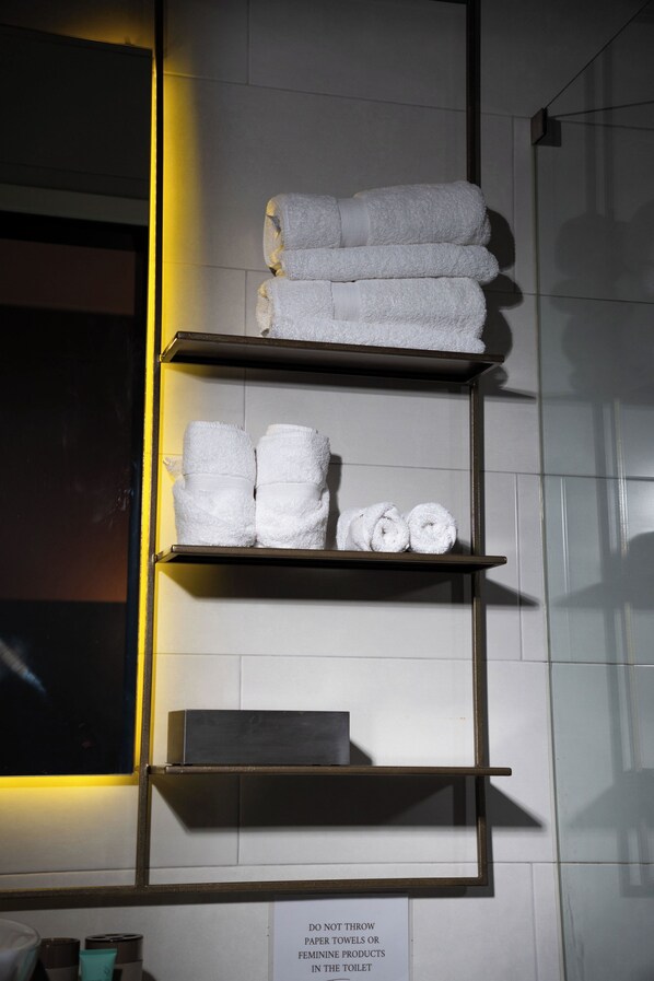 A bathroom with a towel rack holding neatly folded towels. - Olivar House Hotel (Lima)