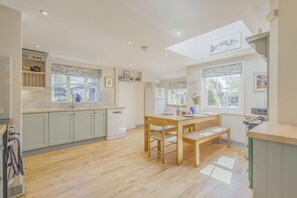 Una cocina moderna con suelo de madera, una mesa de comedor y un tragaluz.