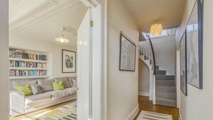 A hallway with a staircase, a bookshelf, and a sofa. - 3 Bed in Woodbridge (oc-sfdor) (Woodbridge)