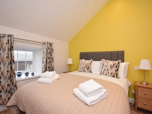 A bedroom with a bed, pillows, a nightstand, a lamp, and a window with curtains. - 1 Bed in Alnwick (oc-80486) (Newton-by-the-Sea)