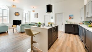 Une cuisine moderne dotée d’un îlot central, de meubles de rangement aux couleurs sombres et d’une grande fenêtre.