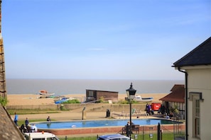 A coastal view with a swimming pool, beach, and ocean.