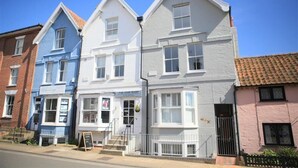 A row of three-story buildings with distinct architectural styles, including a blue building with a sign that reads "The Hair Shop". - 4 Bed in Aldeburgh (oc-sfhan7) (Aldeburgh)