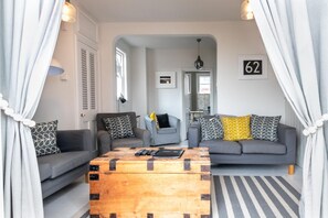 A living room with two sofas, a coffee table, and a door with the number 62.
