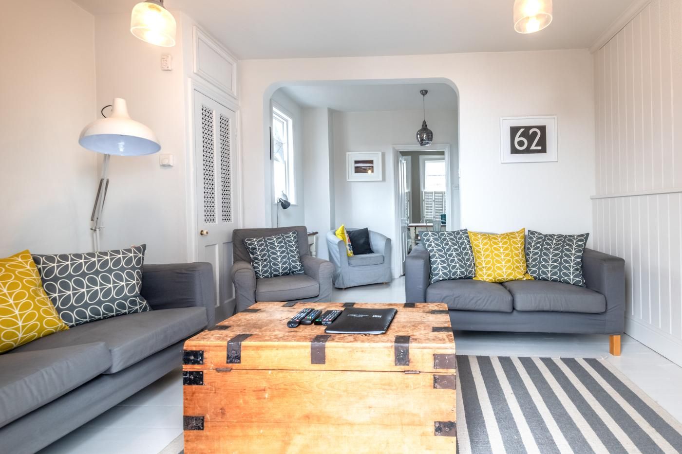 A modern living room with two grey sofas, a wooden coffee table, and a striped rug.