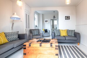 A modern living room with two grey sofas, a wooden coffee table, and a striped rug.