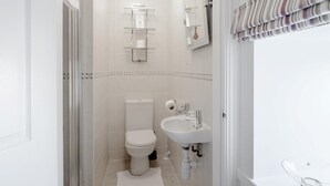 A modern bathroom with a toilet, sink, and glass shelves. - 4 Bed in Alnwick (oc-80496) (Newton-by-the-Sea)
