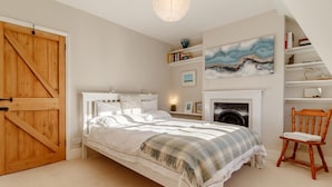 A bedroom with a bed, a wooden door, a fireplace, a bookshelf, and a painting. - 2 Bed in Orford (oc-sflpo) (Orford)