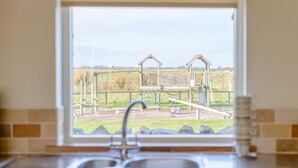 A kitchen with a window view of a playground. - 3 Bed in Alnwick (oc-80489) (Newton-by-the-Sea)