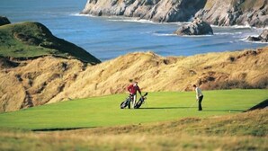 A golf course with a view of the ocean and rocky cliffs. - 1 Bed in Reynoldston (oc-hh508) (Scurlage)