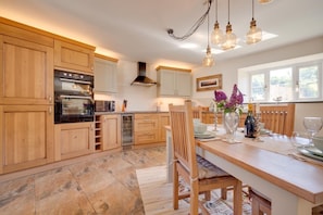 A kitchen with wooden cabinets, a built-in oven, and a dining area with a table set for two.