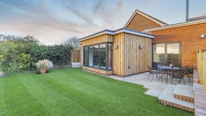 A modern house with a well-maintained lawn, a patio with outdoor furniture, and a brick exterior. - 2 Bed in Snape (oc-sfvin) (Church Common)