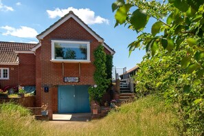 A two-story brick house with a blue garage door, a small front porch, and a sign that reads "Vincent Studio." - 2 Bed in Snape (oc-sfvin) (Church Common)