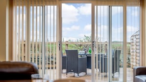 Une pièce dotée d’une porte-fenêtre coulissante donnant sur une terrasse extérieure avec une table et des chaises.