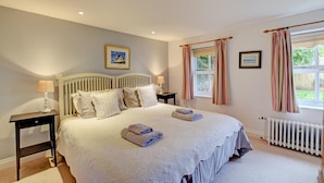 A bedroom with a large bed, two bedside tables, a radiator, and a window with curtains. - 2 Bed in Snape (oc-sfoms) (Snape)