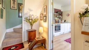 A staircase leading to a kitchen with a vase of flowers, a clock, and a radiator. - 1 Bed in Snape (oc-sfahs) (Snape)