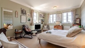 A bedroom with a large bed, a television, a chair, a dresser, and artwork on the walls. - 1 Bed in Snape (oc-sfahs) (Snape)